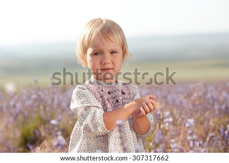 Little girl 2-3 year old wearing rustic style dress. Looking at camera. Posing outdoors. Childhood.