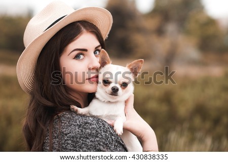 Beautiful young girl 20-24 year old holding pet dog chihuahua outdoors. Looking at camera. Togetherness.