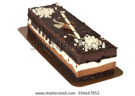 delicious looking chocolate layered mousse cake garnished with white chocolate shavings served on golden paper plate isolated on white background
