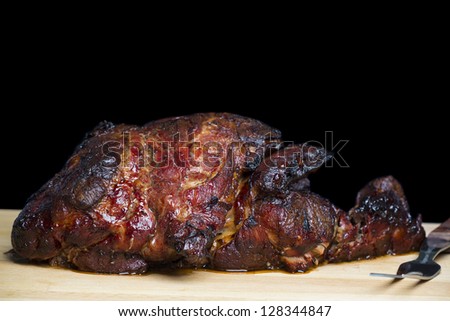 slow roasted pork shoulder butt on wooden cutting board with fork on black background; copy space for your text