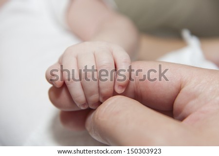 close up of newborn baby hand gripping fathers finger - touch of love
