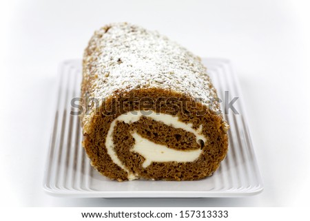delicious freshly baked pumpkin roll cake with cream cheese filling and powdered sugar on top decorated on white plate with copy space for your text