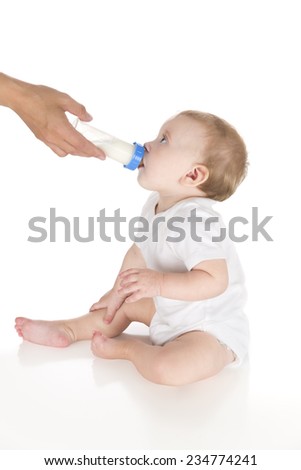 mother feeding milk or formula to very beautiful little infant baby from feeding bottle, sitting and drinking over white background