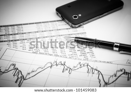data analyzing in stock market: on the charts and quotes prints, the smart phone and a pen