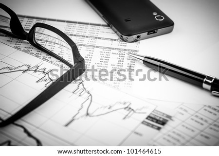 data analyzing in stock market: on the charts and quotes prints, the smart phone, eyeglasses and a pen