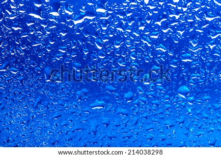 drops of water on glass with blue background down in macro lens shot