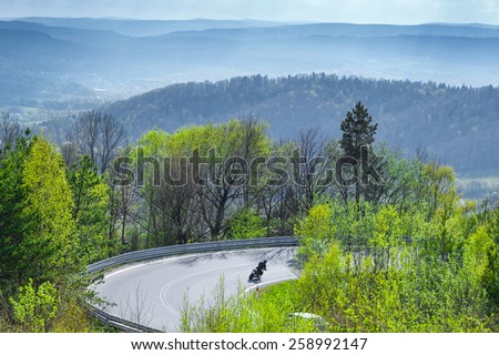 motorcycles riders going down, passing sharp curves, on European mountains roads