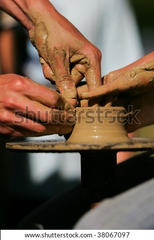 Training to potter's skill on a potter's wheel with damp clay. Close up.