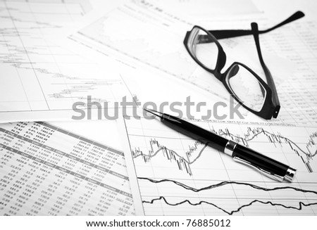 data analyzing in stock market: on the charts and quotes prints, the eyeglasses and a pen