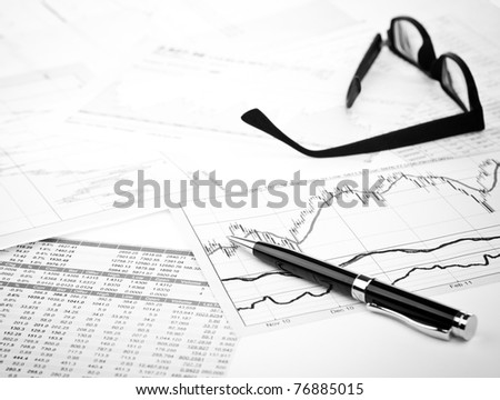 data analyzing in stock market: on the charts and quotes prints, the eyeglasses and a pen