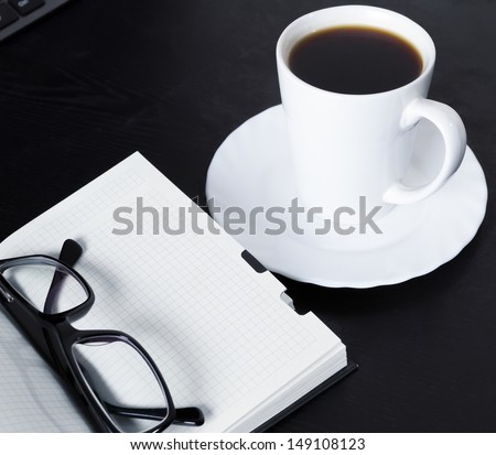 Open Book with glasses and a cup of coffee on black office table. Review of the side