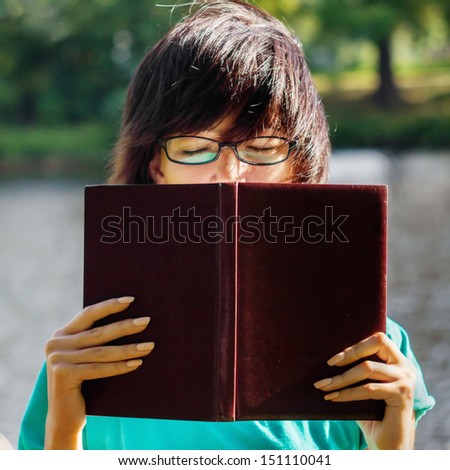 Woman resting with eyes closed having covered book in park