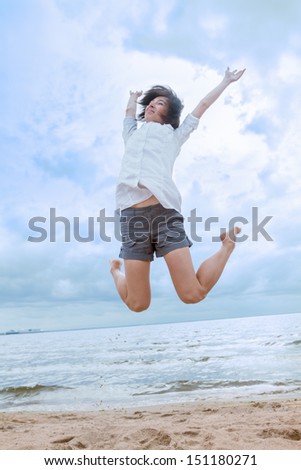 Beautiful woman jumping for joy on the beach