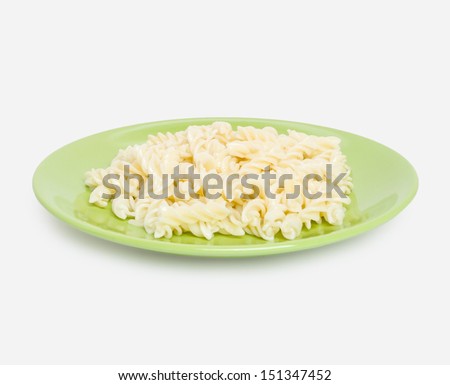 Cooked macaroni in the shape of a spiral on the green plate, side view