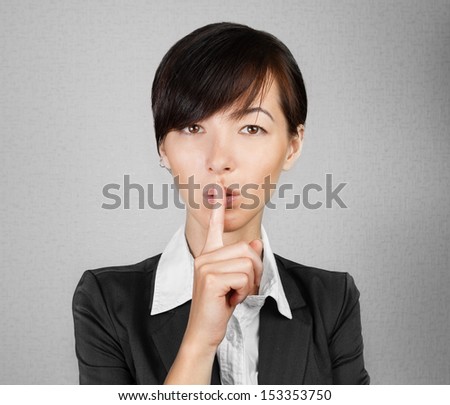 Businesswoman making silence sign on gray background