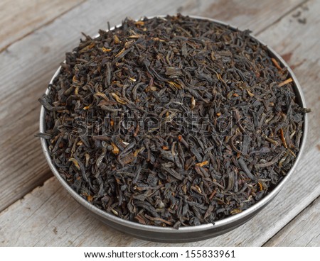Black leaf tea on a wooden background, top view
