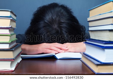 Woman sleeps between stacks of books