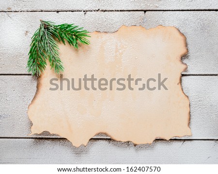 Christmas tree branch on the corner of old paper on a snowy table, copyspace