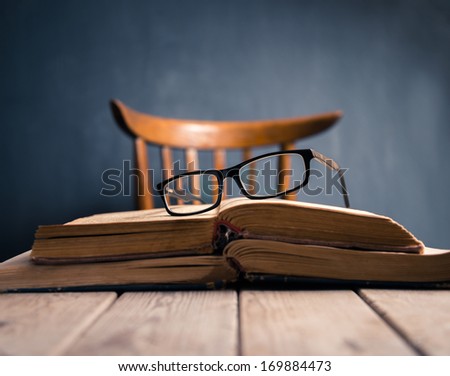 Old books and glasses  on a wooden table of  teacher. Focus on glasses