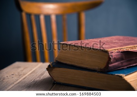 Two old books on a wooden table in a classroom