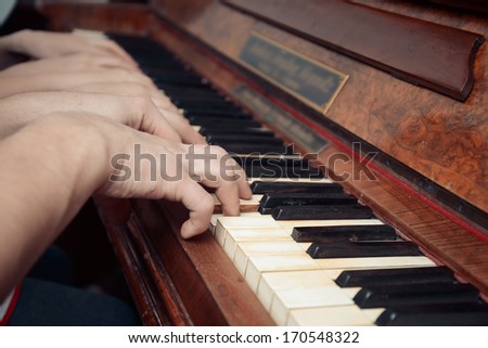 Family of three people is playing the piano, side view, face is not visible