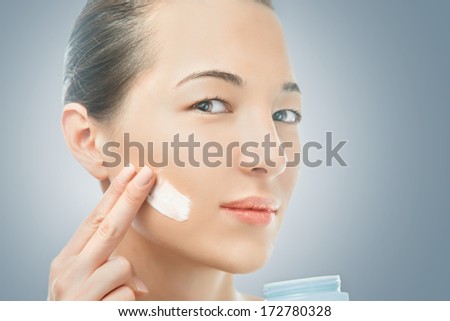 Woman applying cream on the face, concept of beauty skin