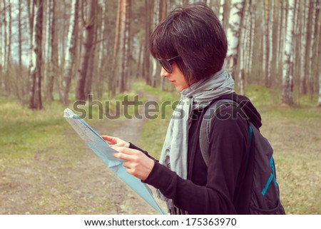 Young woman traveler looks at map in a forest