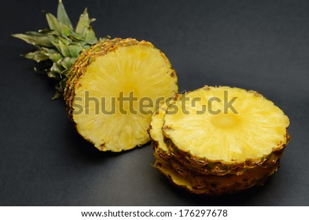 Sliced round ripe pineapple on a black table