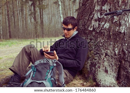 Man traveler searches GPS coordinates on the mobile phone in the forest