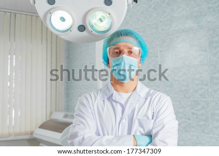 Man doctor surgeon in a mask and cap stands in an operating room