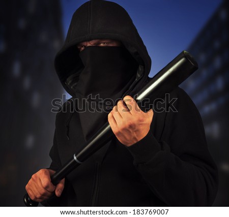 Dangerous man with baseball bat ready for fight on the background of night city