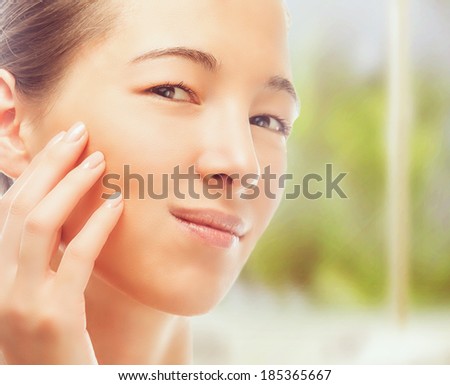 Beautiful young woman touches face with smooth skin, concept of skincare
