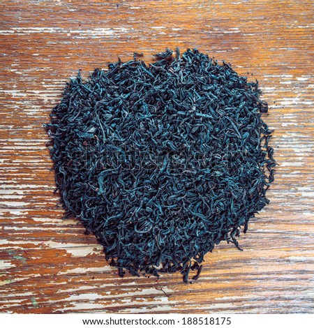 Heap of black leaf tea on a wooden background