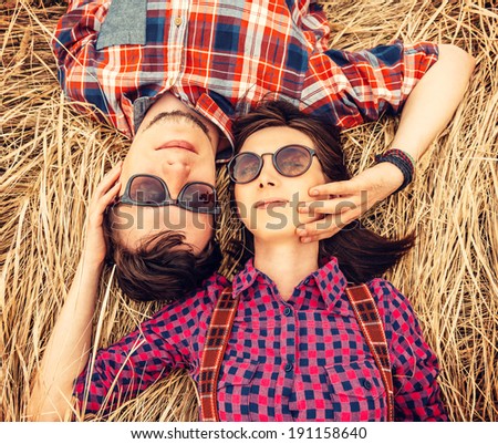 Beautiful couple in love is lying on the dry grass, top view