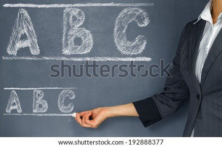 Unrecognizable woman teacher points to the ABC alphabet on blackboard