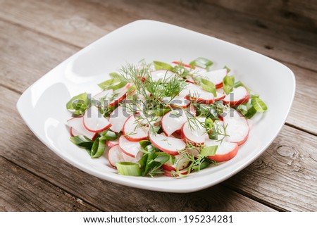 Healthy radish salad in white plate on wooden table