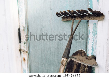 Gardening tools: hoe, shovel and rake near a shed