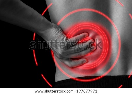 Man touches the lower back, pain in the kidney, monochrome image, close-up, pain area of red color