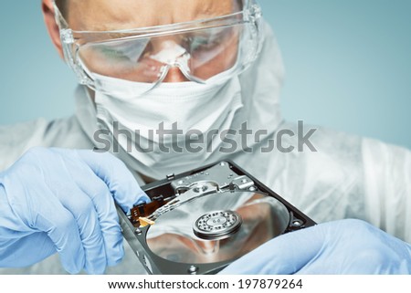 Man technician in glasses and gloves is analyzing the hard disk, repair computer