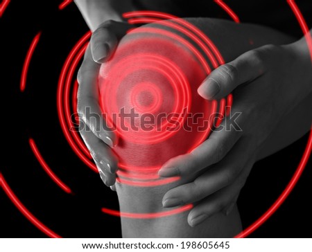 Woman holds her knee, pain in the knee joint, monochrome image, pain area of red color