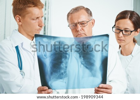 Senior man doctor and young doctors examine x-ray image of lungs in a clinic