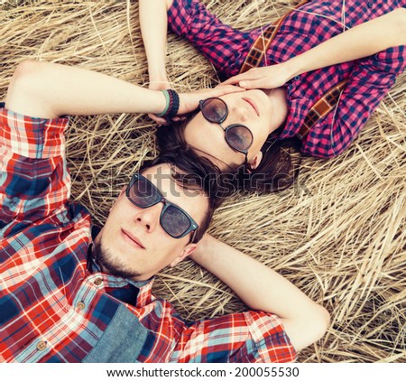 Beautiful couple in love is lying on dry grass, man is stroking the face of girl