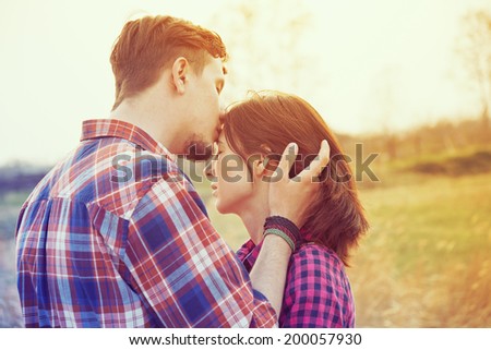 Young man kisses a woman in the forehead, image with vintage instagram filter