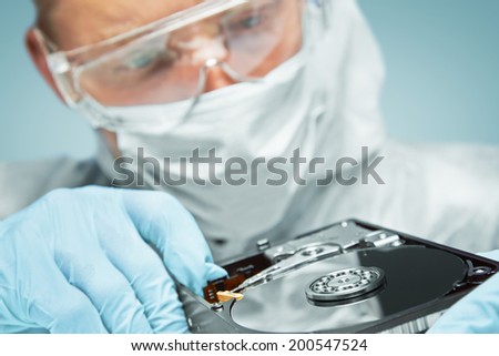 Man scientist in glasses examines the hard disk, repair computer. Focus on hard disk