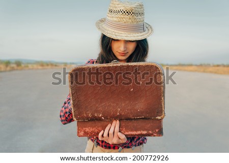 Young beautiful woman looking for something in the open suitcase, theme of travel