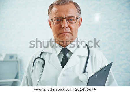 Portrait of older man doctor with documents in hospital