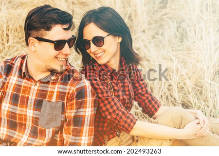 Happy couple in love is sitting on hay, hipster style