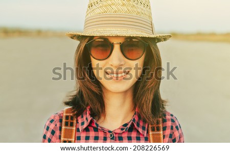 Portrait of happy hipster style girl in hat and sunglasses outdoor. With vintage filter