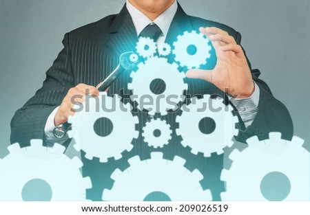Unrecognizable businessman holds metal wrench with cogwheels, concept of business creation