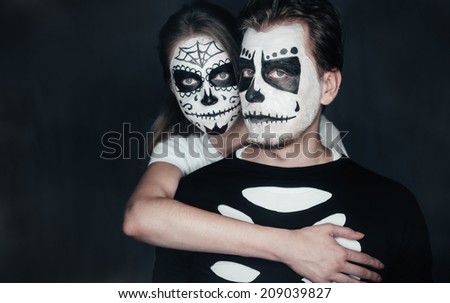 Couple in love with dark skull makeup on black background. Halloween face art